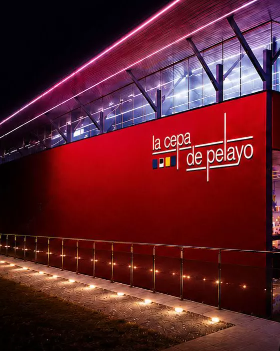 Fachada roja de la bodega La Cepa de Pelayo, iluminada de noche